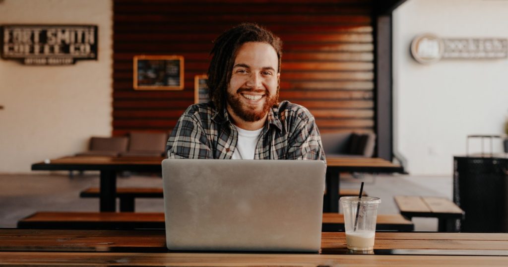 A man smiles as he sits at a computer. WFM can help you improve your Agent Experience through more effective resource management.