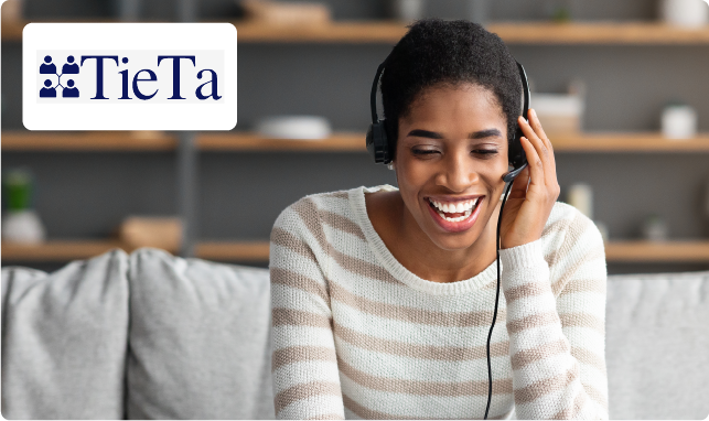 A woman smiles as she talks into a headset. TieTa's logo is positioned in the top left corner.